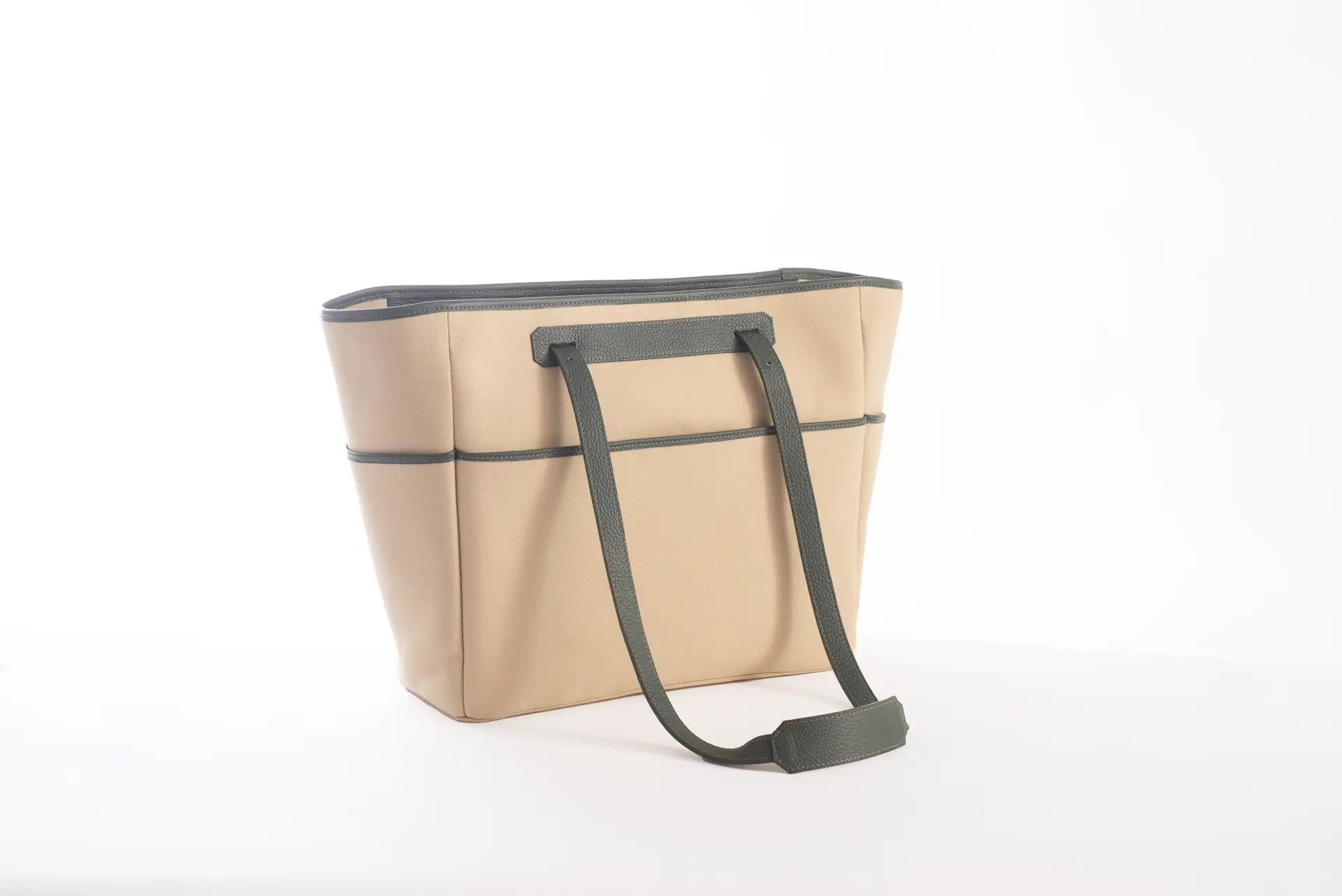 Vista laterale della borsa Liber_TO di Lemanì in color beige con finiture e spallacci in pelle verde, su sfondo bianco. La borsa Lemanì Liber_TO unisce eleganza e praticità, ideale per un look sofisticato.